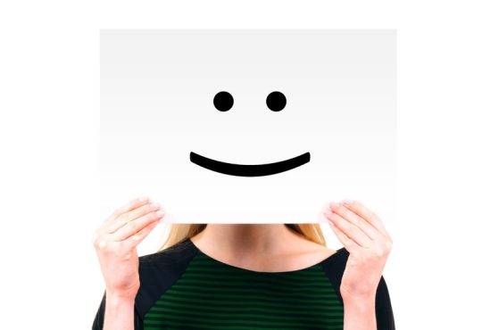 Personne qui tient une pancarte avec un sourire dessiné dessus