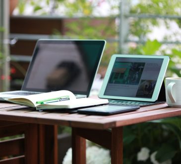Deux portables ouverts sur une table accompagnées d'un carnet d'écriture.