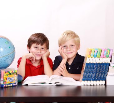 Deux jeunes étudiants entourés de livres qui sourient.