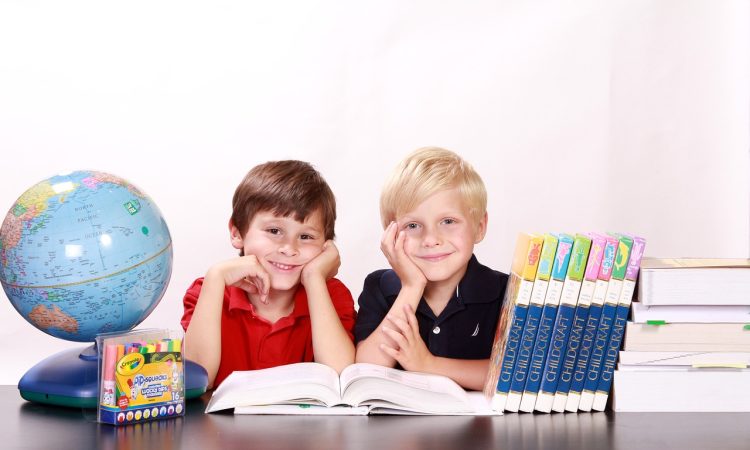 Deux jeunes étudiants entourés de livres qui sourient.